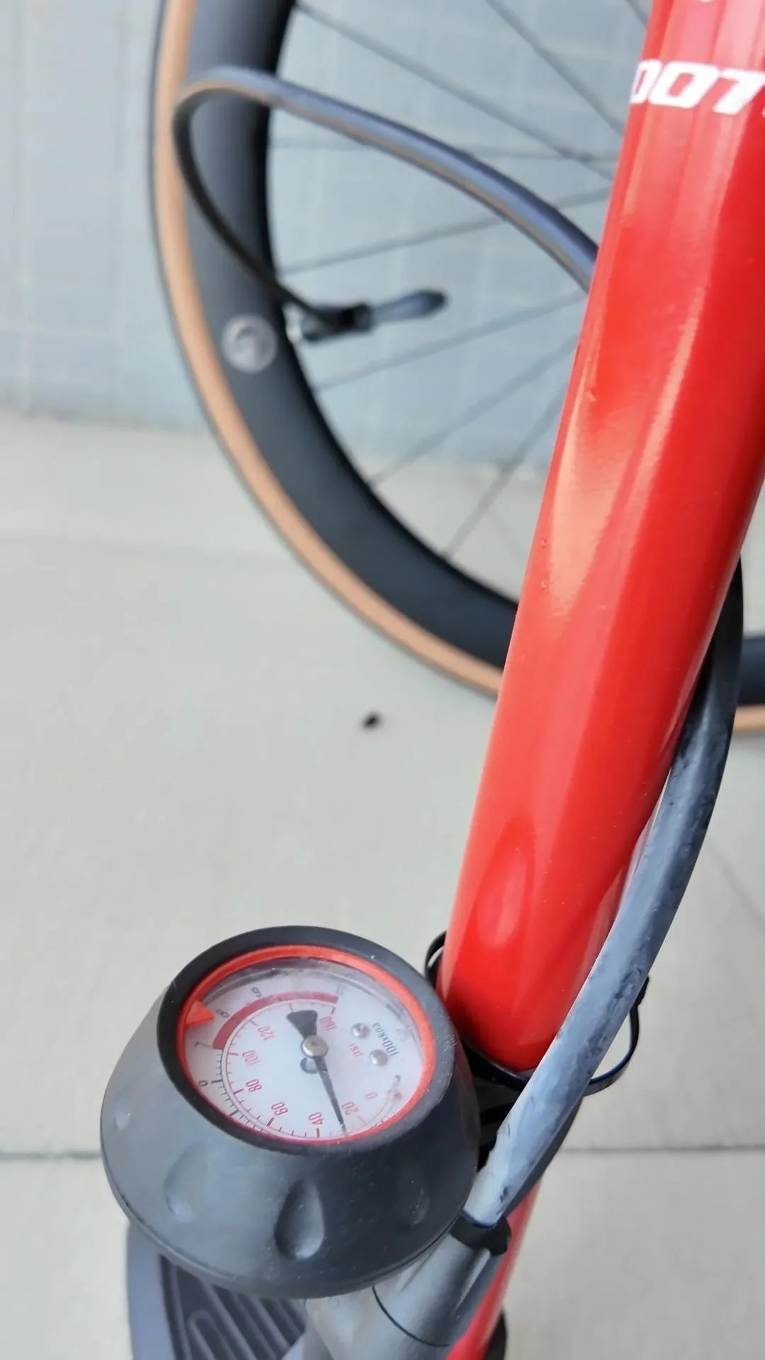 Close-up of a tire pressure gauge on a red SAVA Carbon bike with a black wheel in background