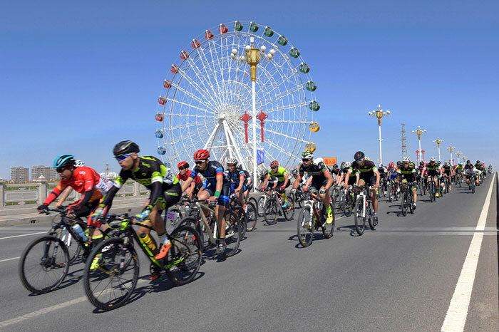 Cyclists racing on carbon road bikes with Ferris wheel in background, SAVA Carbon Bike event