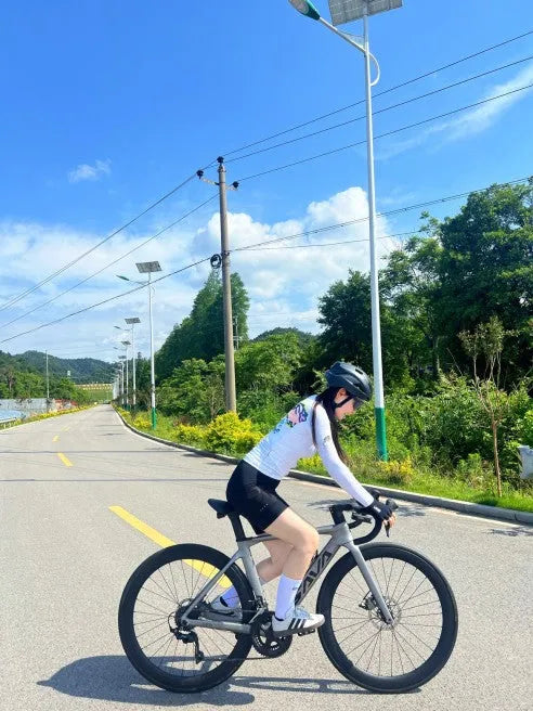 Cyclist riding SAVA carbon road bike on sunny outdoor trail with trees and blue sky