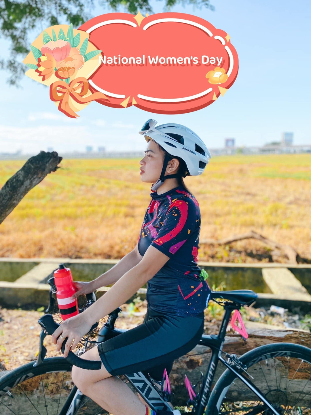 Woman in cycling gear on SAVA carbon road bike outdoors, National Women's Day banner above