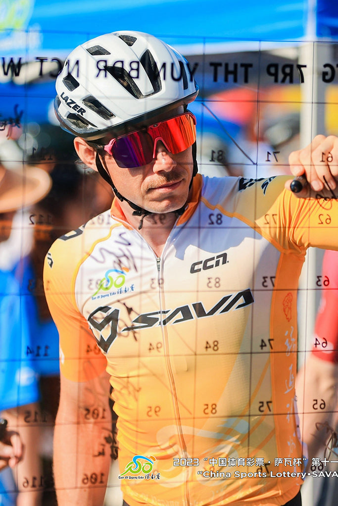 Cyclist in SAVA Carbon Bike gear signing race board at outdoor cycling event