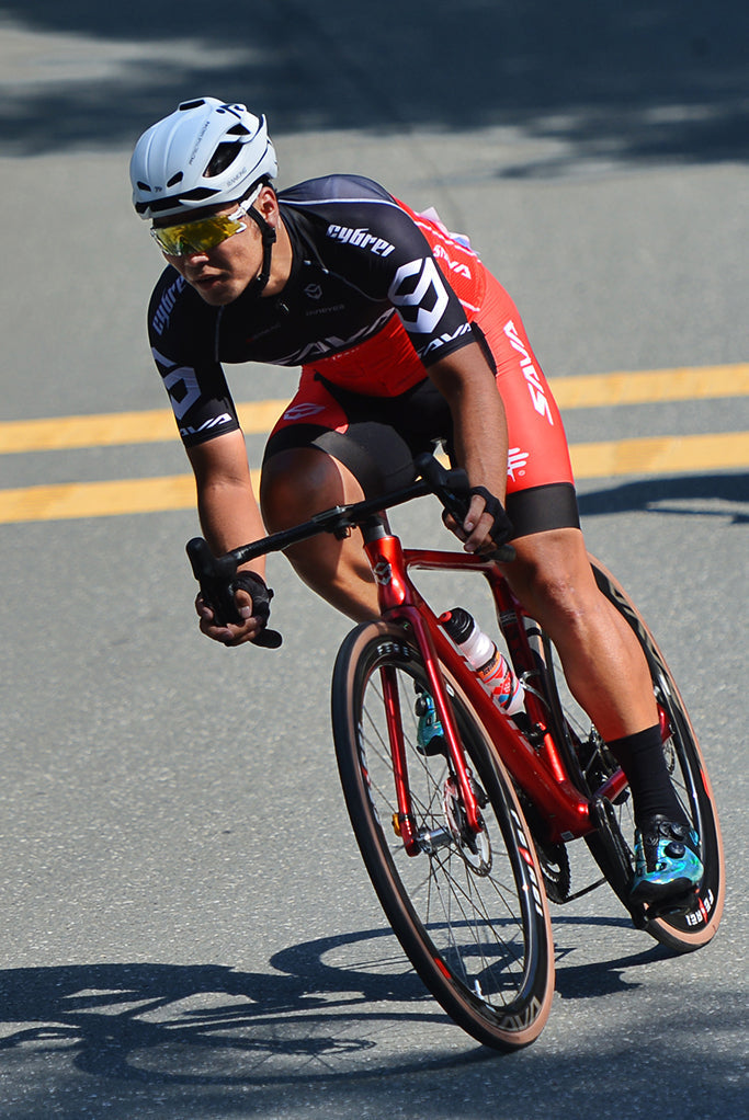Cyclist riding SAVA carbon road bike on asphalt, wearing helmet and cycling gear